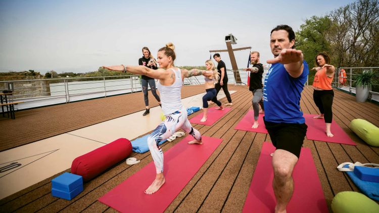 Fitness guru Christmas Abbott (in white tank top) practices yoga on the Amadeus Provence.