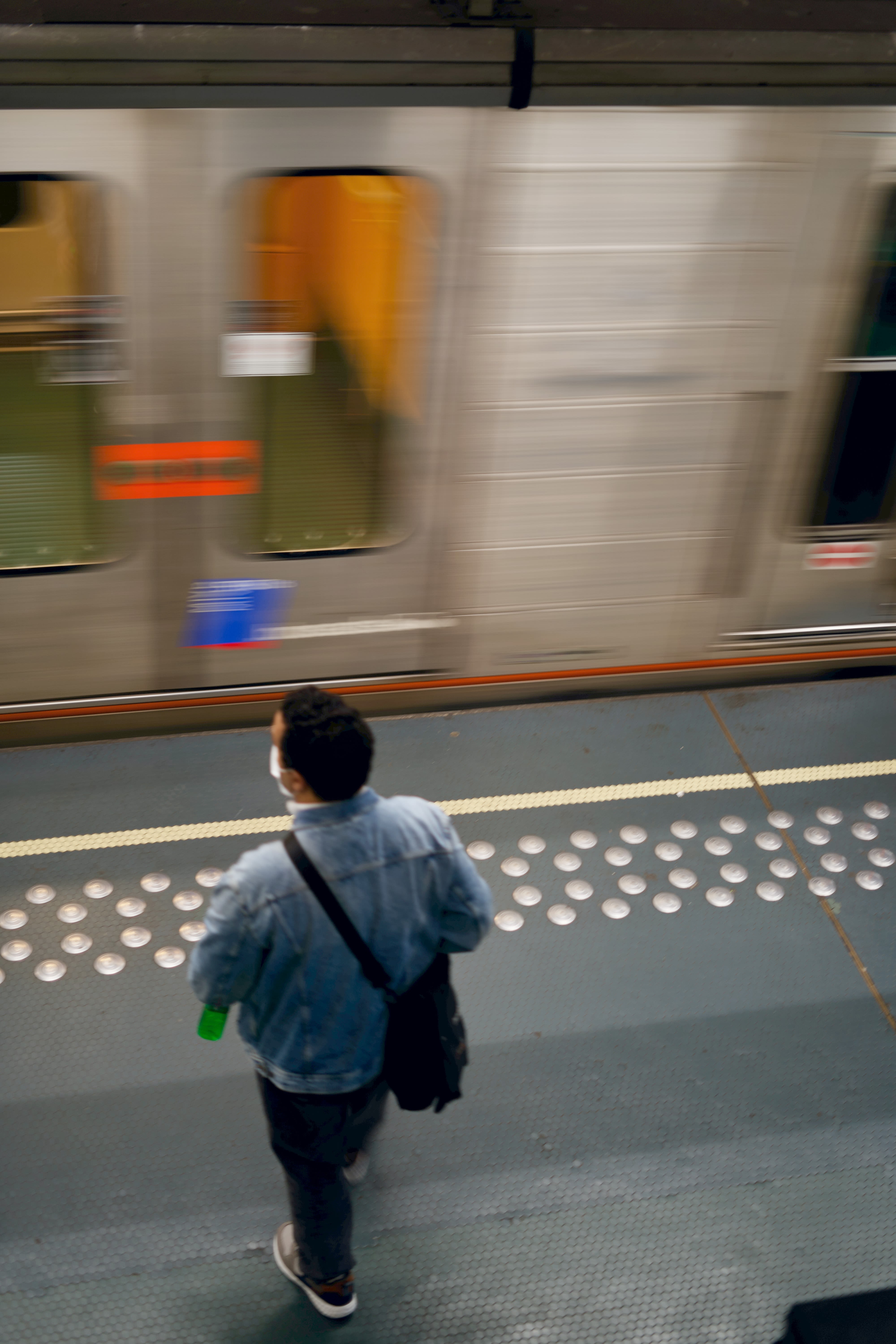 man in blue jacket standing on train station