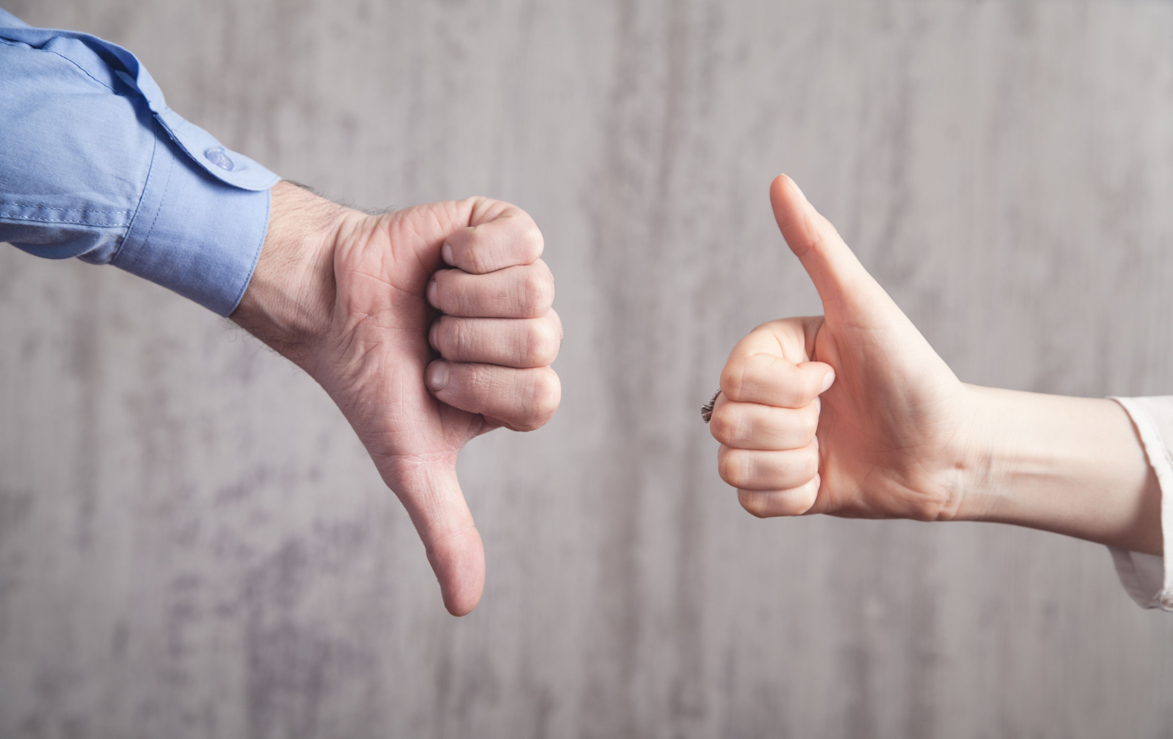 A hand showing a thumbsdown and a hand showing a thumbs up