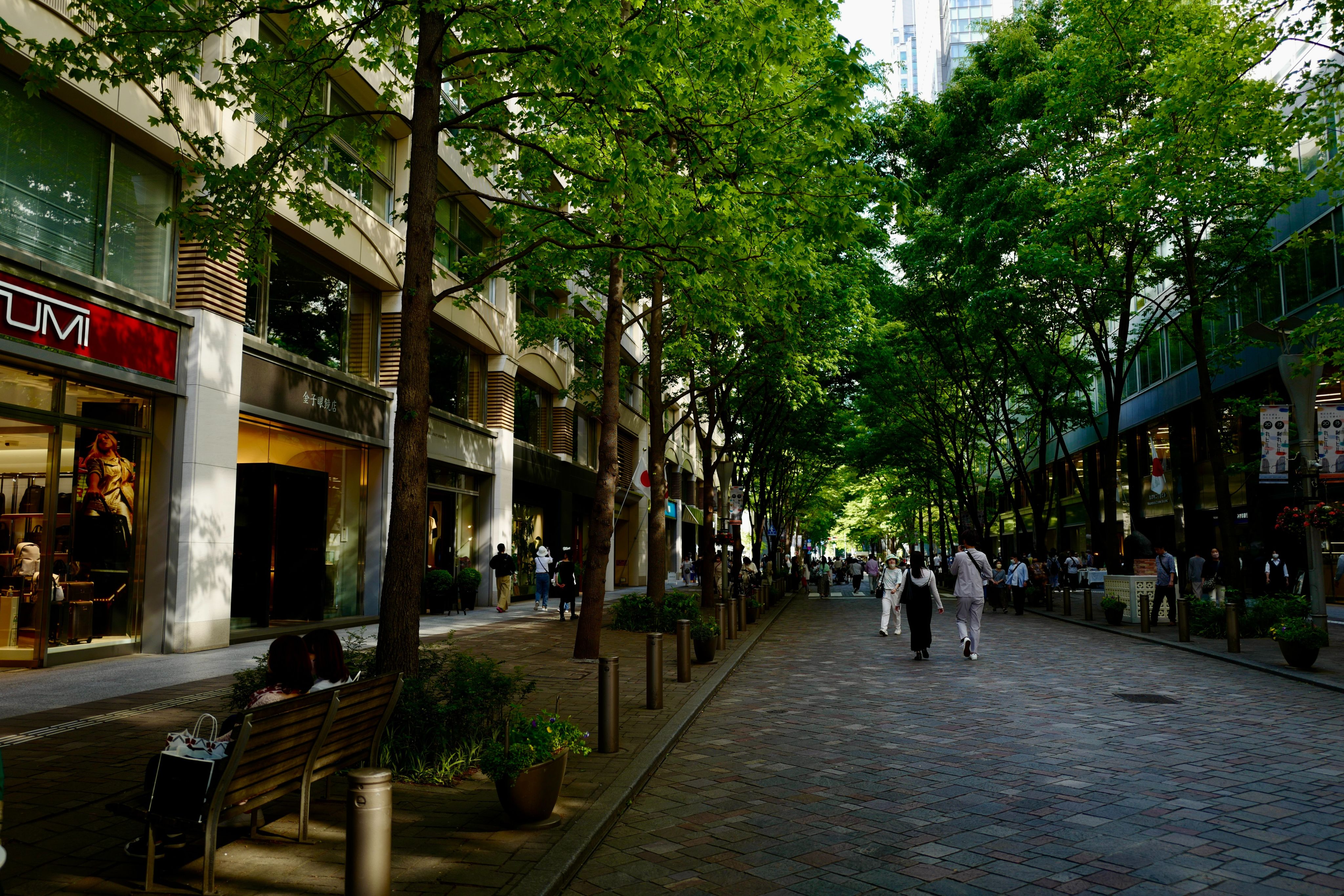 a group of people walking down a street next to tall buildings
