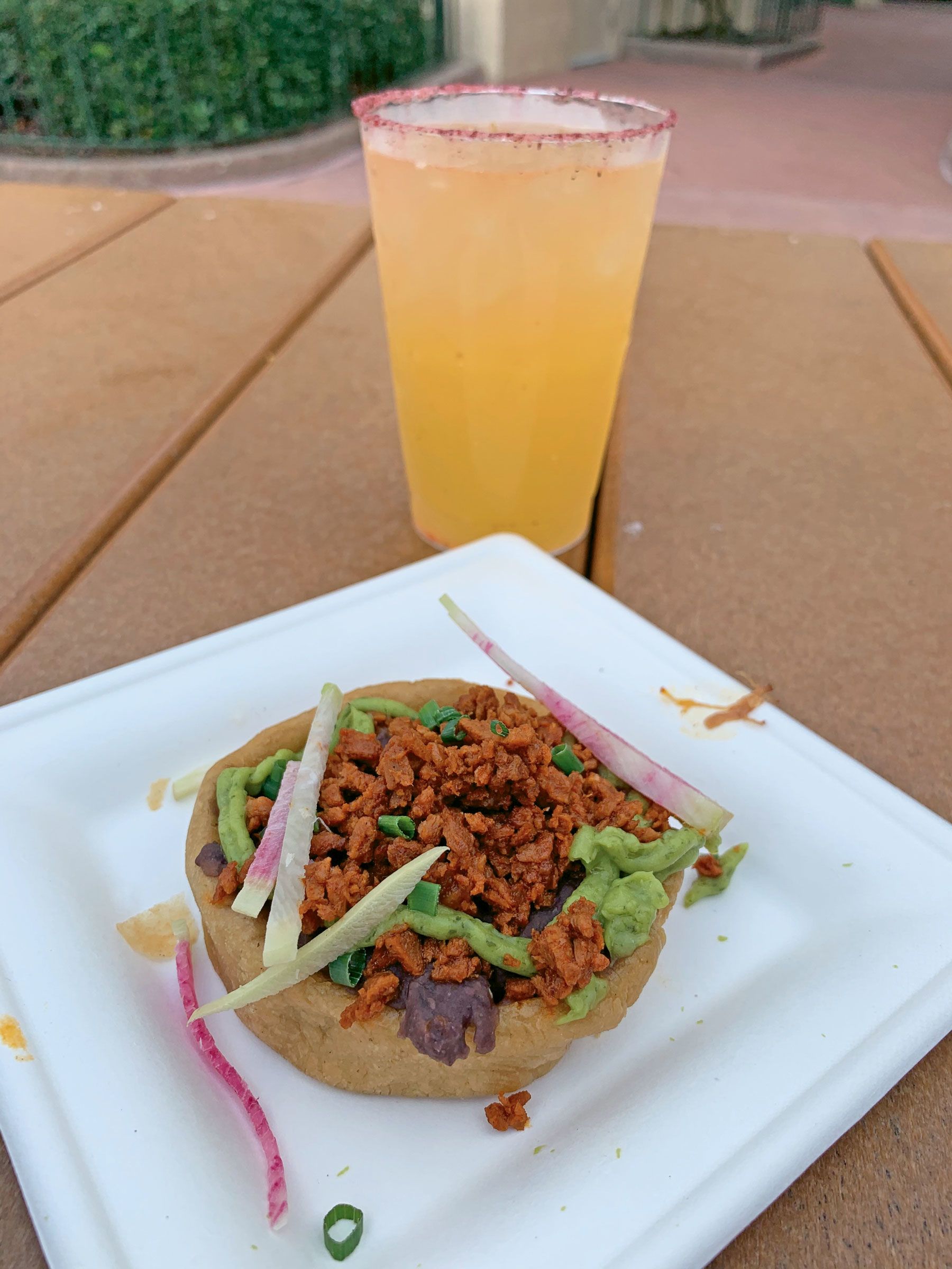 The sope de chorizo from the 2021 Taste of Epcot International Flower and Garden Festival. The plant-based dish consists of plant-based ground chorizo on fried corn dough with black beans and avocado mousse, and is seen here with a passion fruit margarita. (TW photo by Jamie Biesiada)