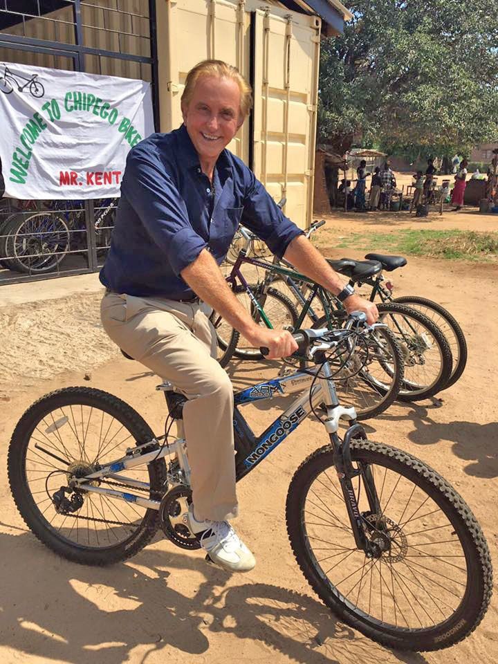 Abercrombie & Kent founder Geoffrey Kent on a bike in Zambia, where Abercrombie & Kent Philanthropy helps women establish bike sales and repair shops.