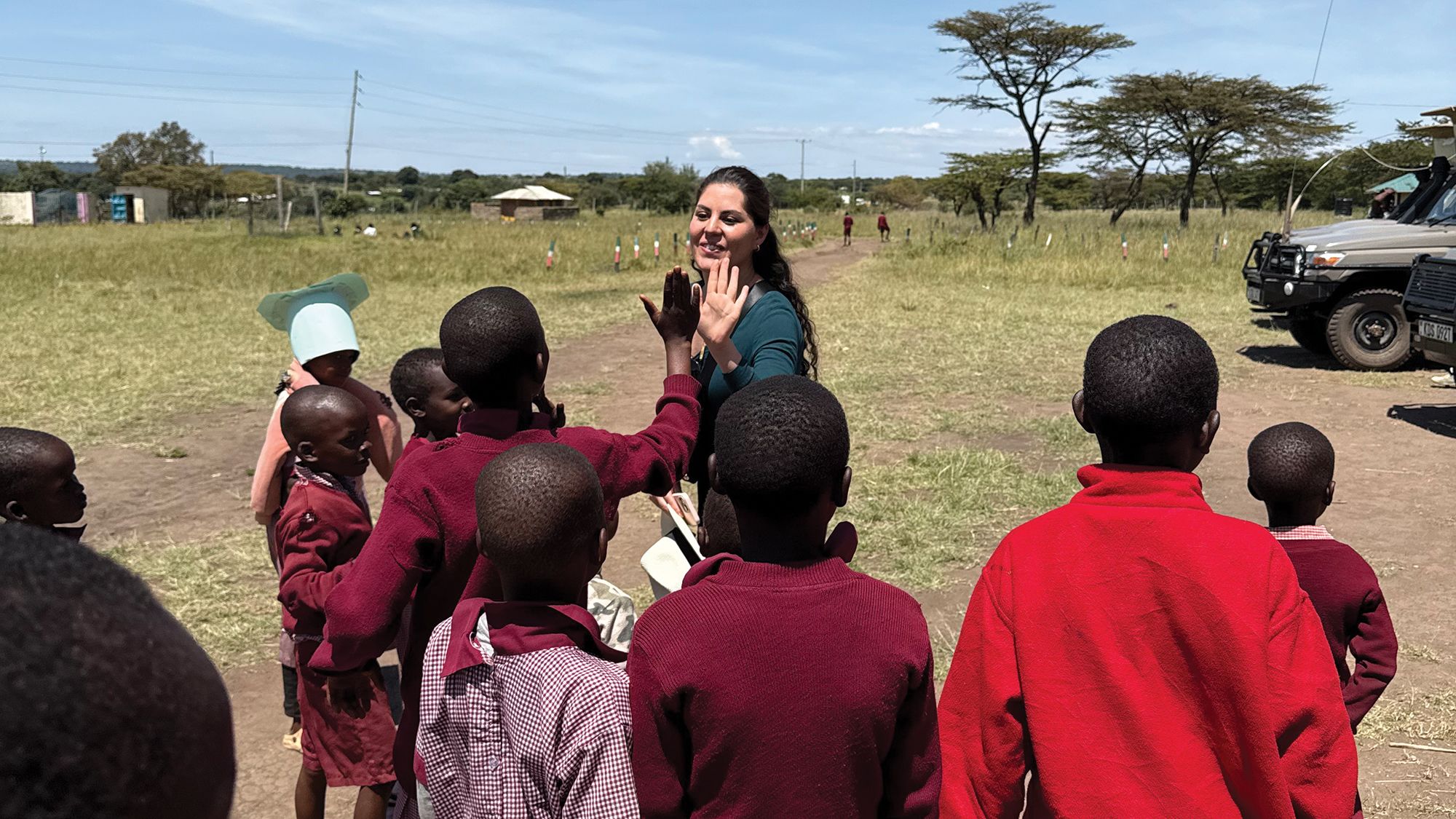 Sandra Solis, Abercrombie & Kent Philanthropy’s (AKP) coordinator in Peru, high-fives students in Kenya’s Masai Mara. (Photo by Jeri Clausing)