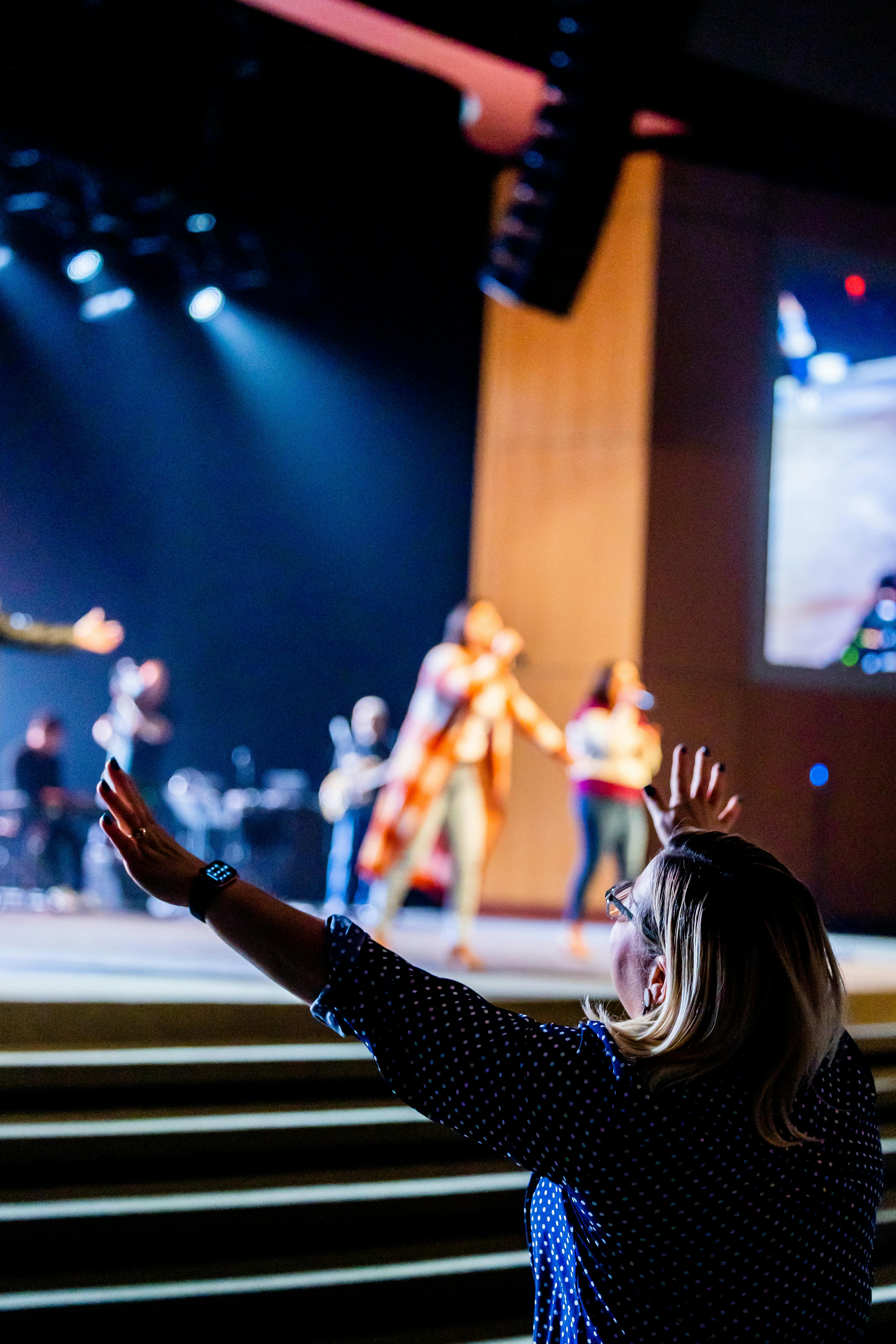 A vibrant live music performance with an audience member raising arms, showing enjoyment.