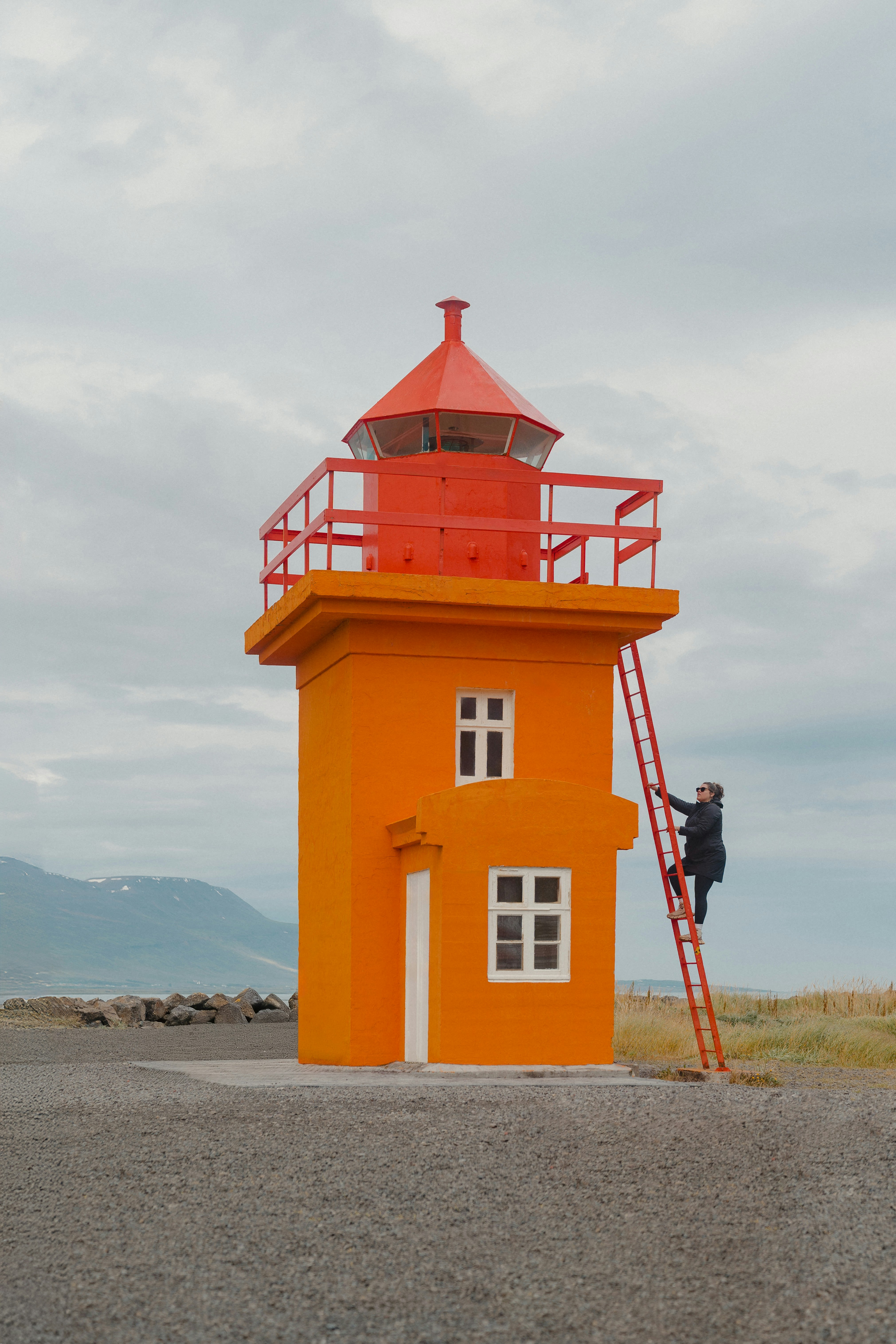 A red and yellow lighthouse on a cloudy day