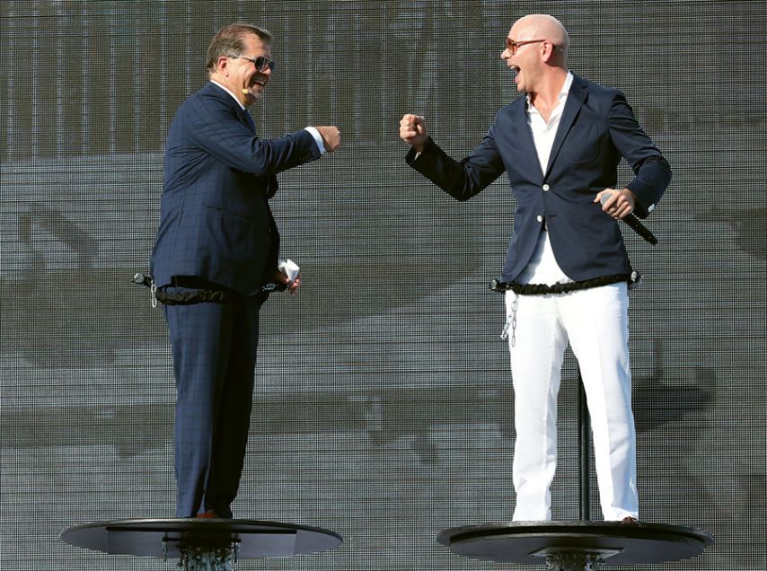Pitbull, right, fist-bumps with Norwegian Cruise Line Holdings CEO Frank Del Rio on elevated platforms at the christening of the Norwegian Escape in 2015.