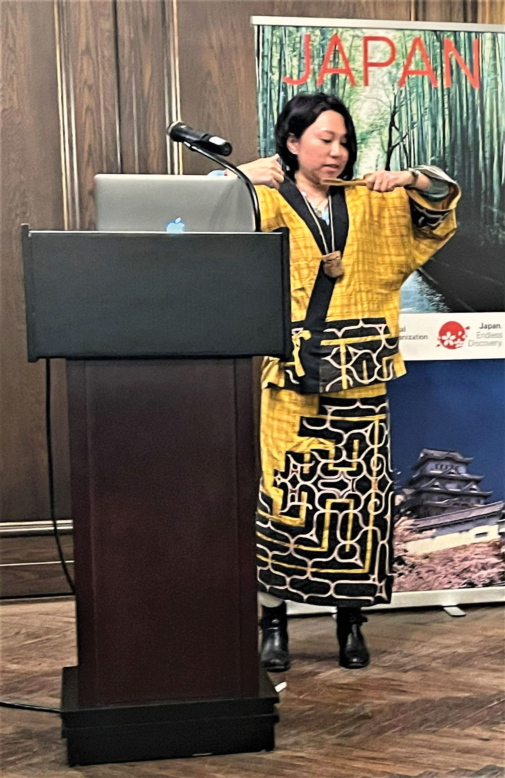 Documentary filmmaker Naomi Mizoguchi, wearing traditional clothing of Japan's indigenous Ainu people, demonstrates how to play the Ainu mukkuri mouth harp at an event organized by the Japanese National Tourist Board. (TW photo by Arnie Weissmann)
