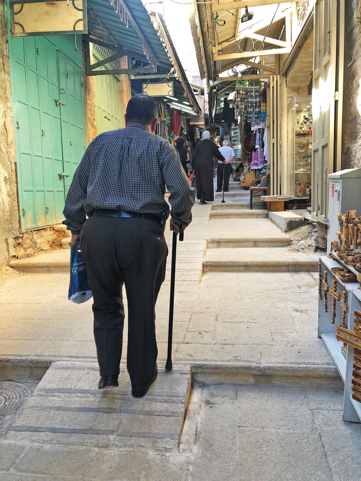A man walks up a ramp with the help of a cane