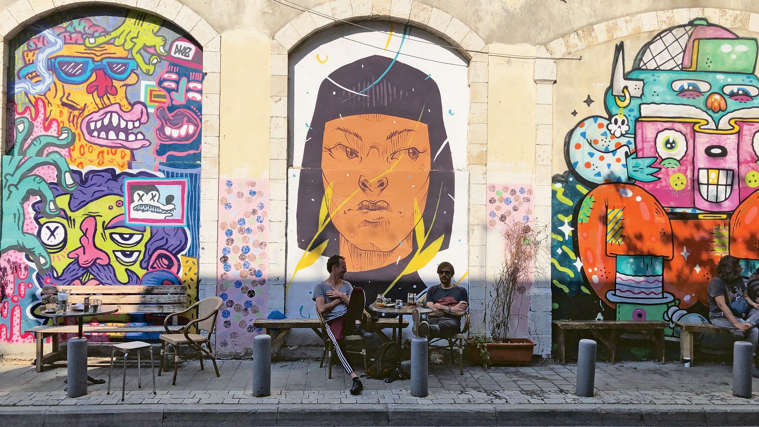 Tel Avivians drink coffee on a street in Old Jaffa. Tel Aviv and Jaffa are full of colorful street murals. TW photo by Johanna Jainchill